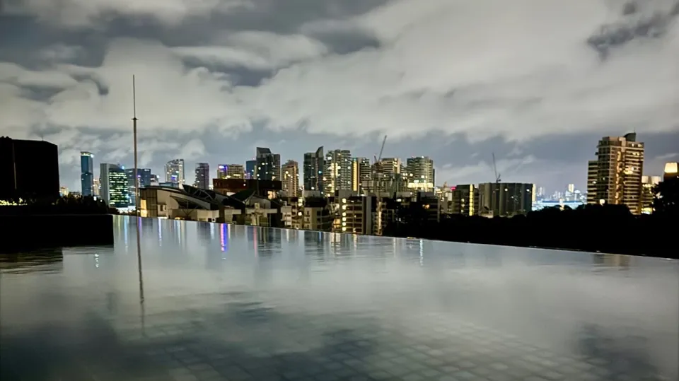 A city skyline reflected in a rooftop pool at night